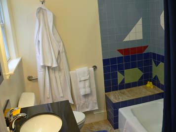 tub enclosure with tile mural, vanity, toilet with grab bars